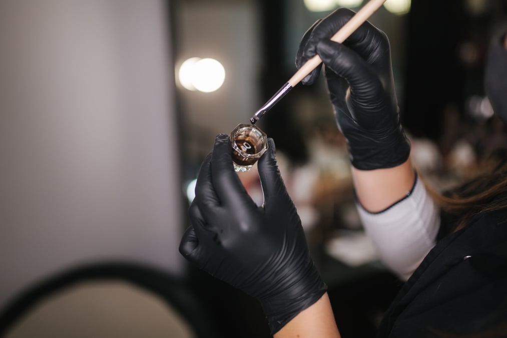 Hands in Black Gloves Using Brush and Henna for Eyebrows